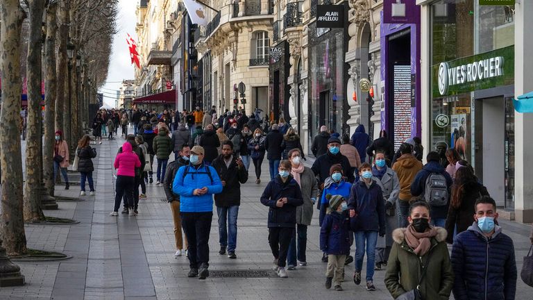 People wearing face masks walk along the Champs Elysees in Paris