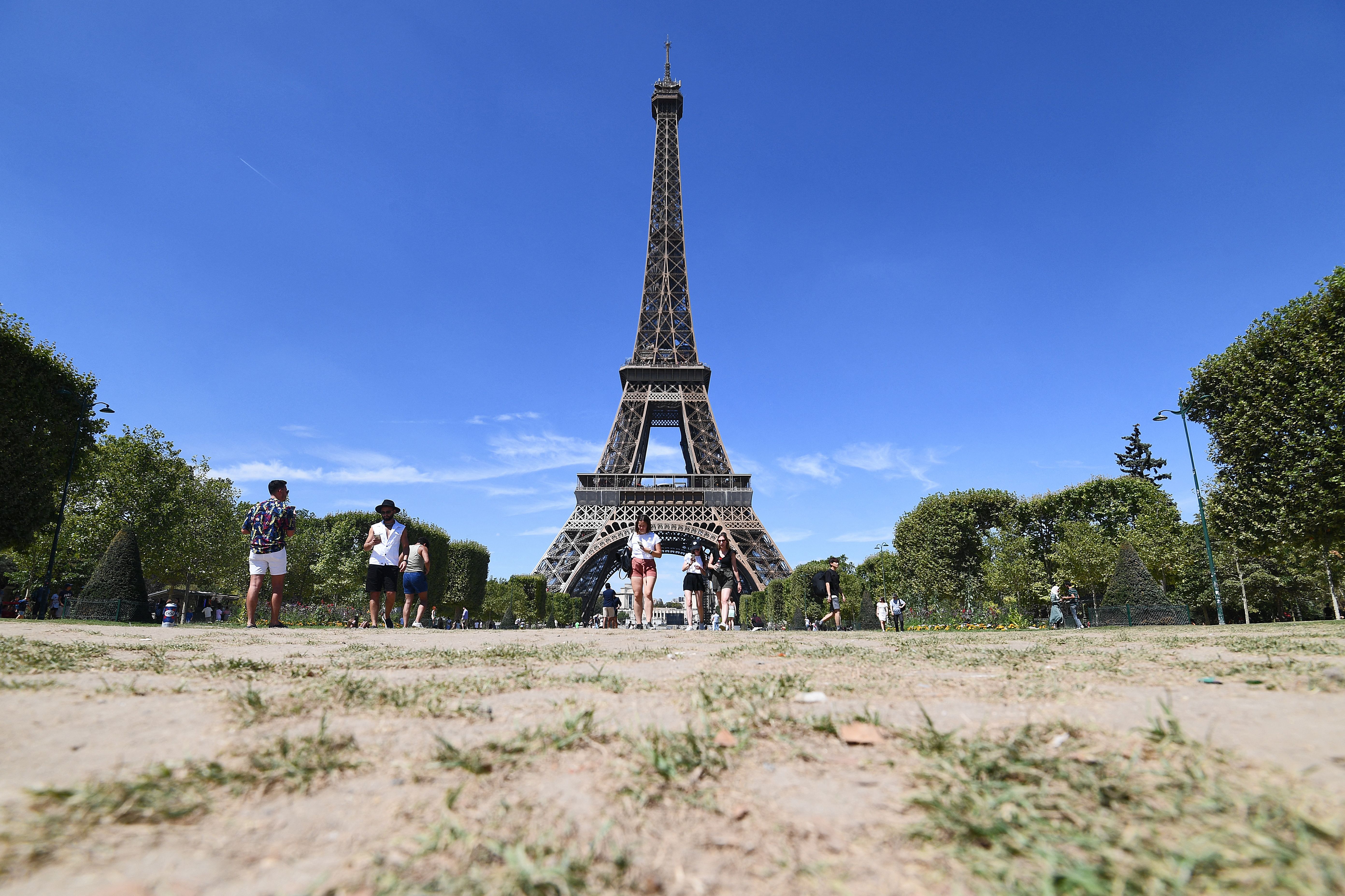 People walk on the parched Champ de Mars in front of the Eiffel Tower in Paris August 3 after France recorded its driest July on record.