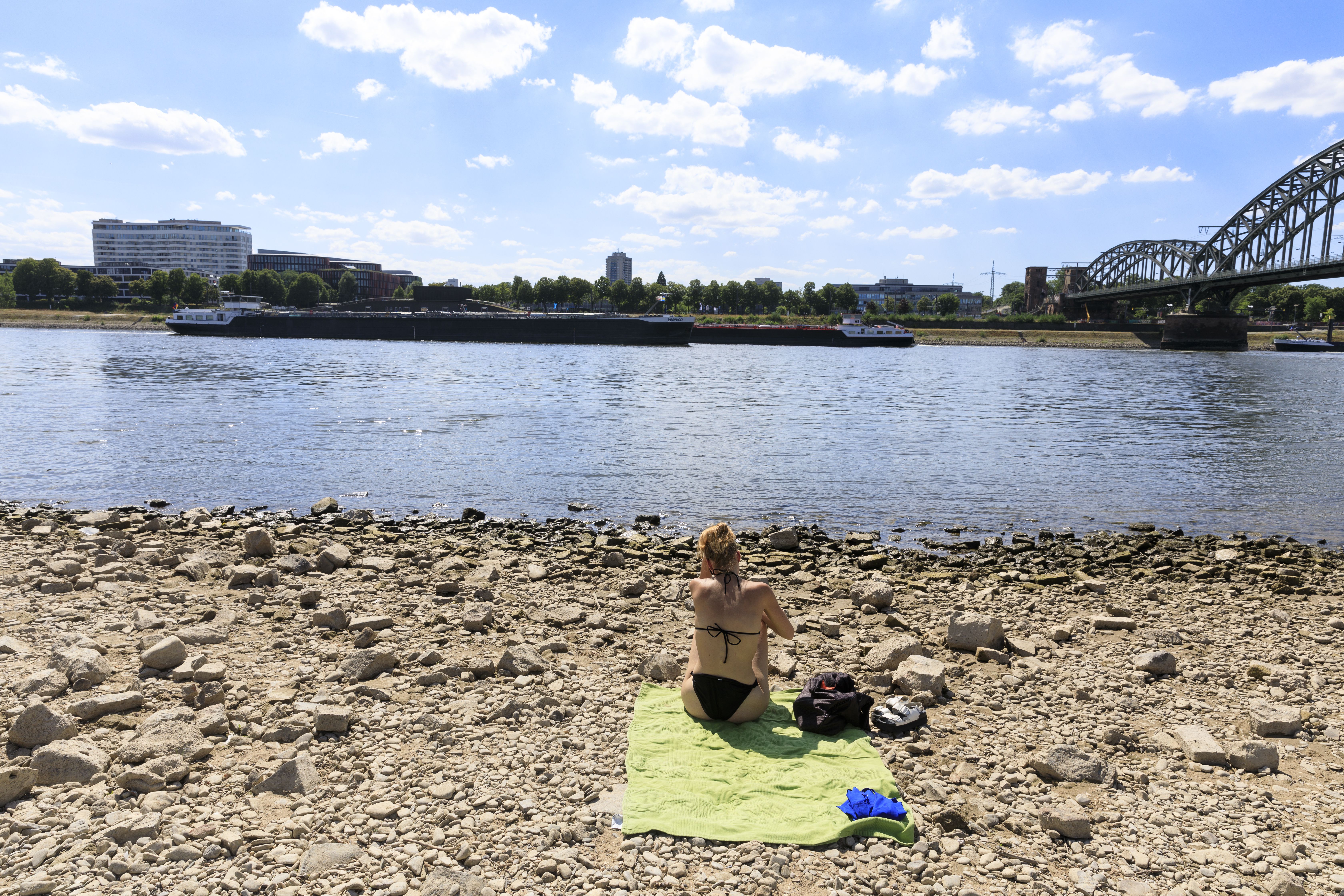 People sit on the dry banks of the Rhine on August 3, 2025 in Cologne, Germany.